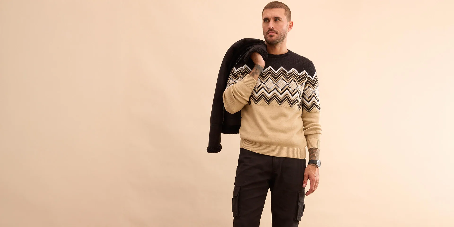 Stilfull look med svart vinterjacka, mönstrad tröja och jeans för kalla dagar.