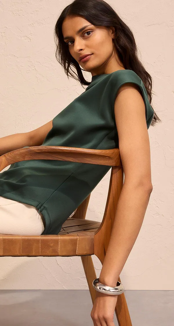 Elegant mörkgrön topp kombinerad med ljusa byxor.