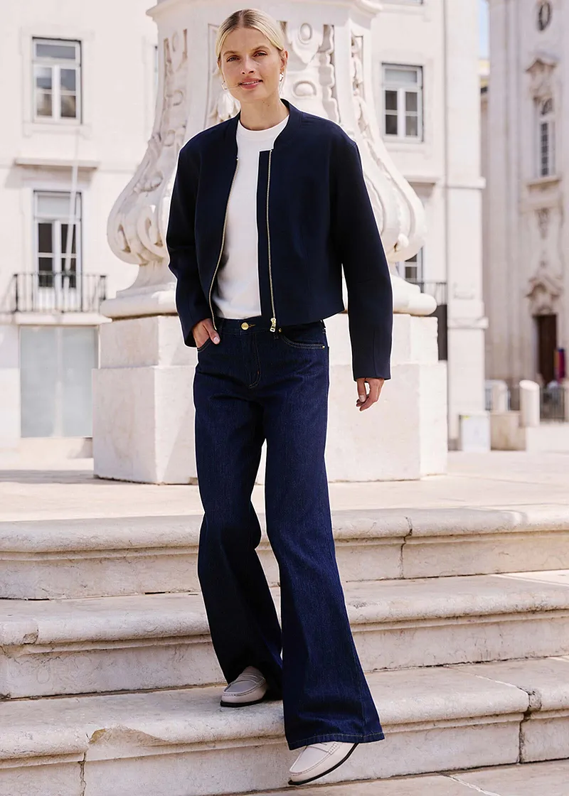 Elegant look med mörk jacka, vit topp och vida jeans.

.