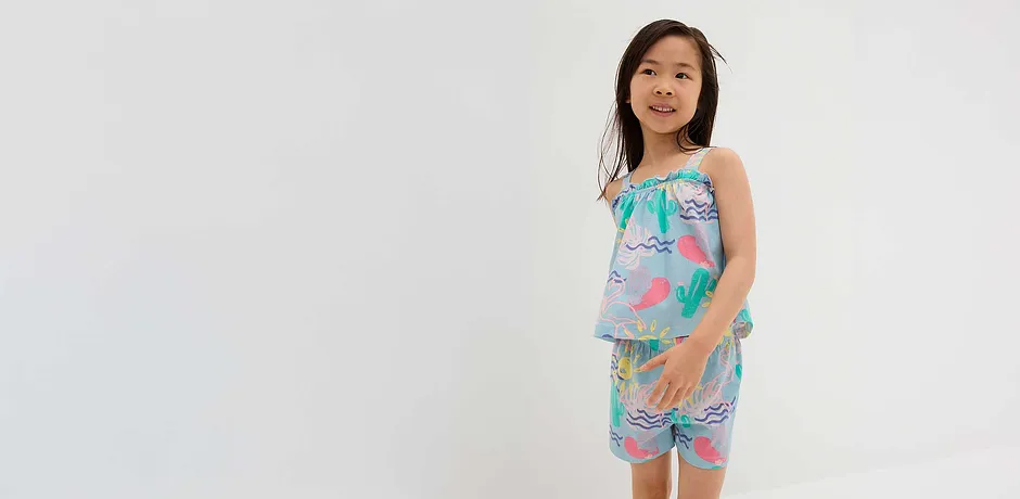 Somrig outfit med topp och shorts i pastellfärger med flamingo- och kaktusmönster.
