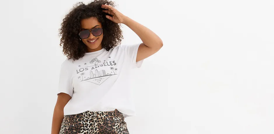 Lös vit T-shirt med tryck, kombinerad med en kjol med leopardmönster. Solglasögon som accessoar.