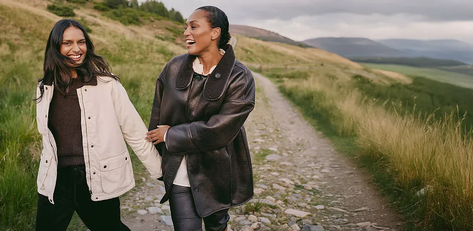 Elegant, brun kappa i skinn med stor krage kombinerad med en ljus topp och mörka byxor.
