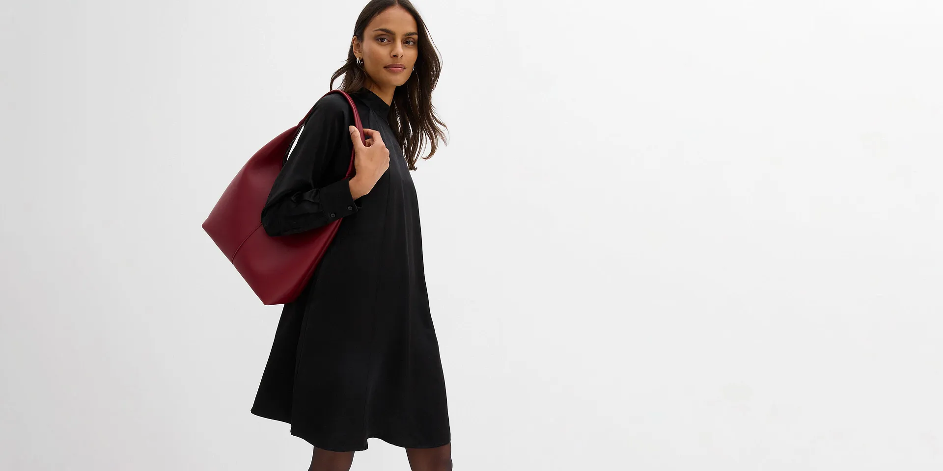 Svart klänning med hög krage och vit kragdekoration. Kort längd och långärmad.

