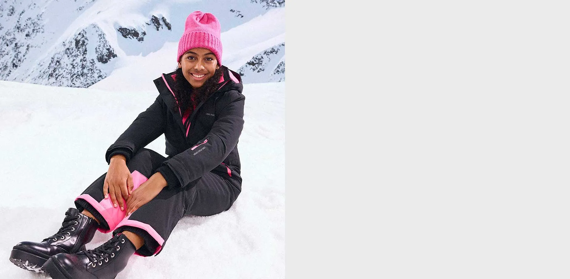 Svarta vinterjacka och byxor, rosa mössa.