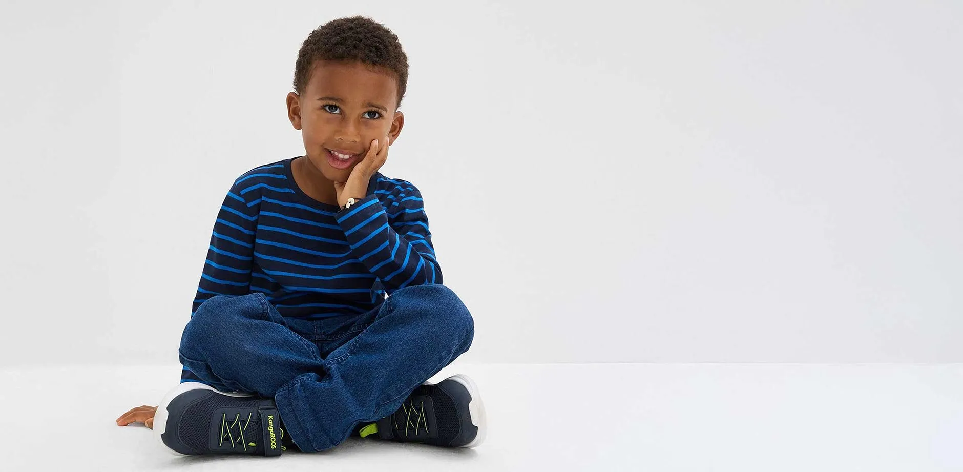 Pojke b&auml;r randig l&aring;ng&auml;rmad tr&ouml;ja.

