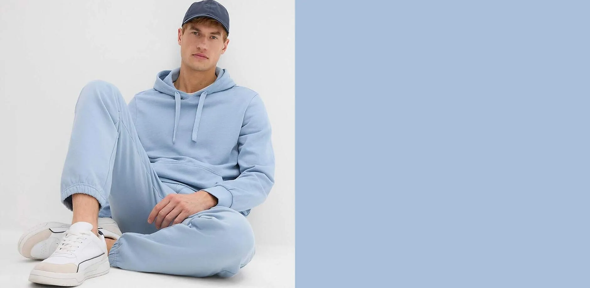 Huvtr&ouml;ja och joggingbyxor. Till det vita sneakers och m&ouml;rk baseballkeps.

