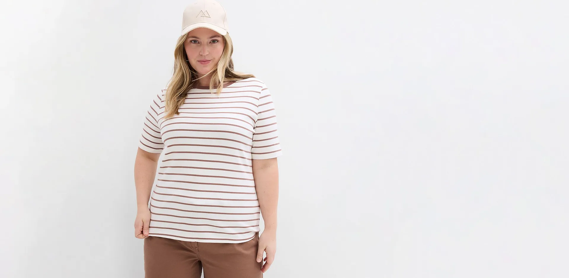 Randigt T-shirt i vitt och brunt, kombinerat med bruna byxor.

