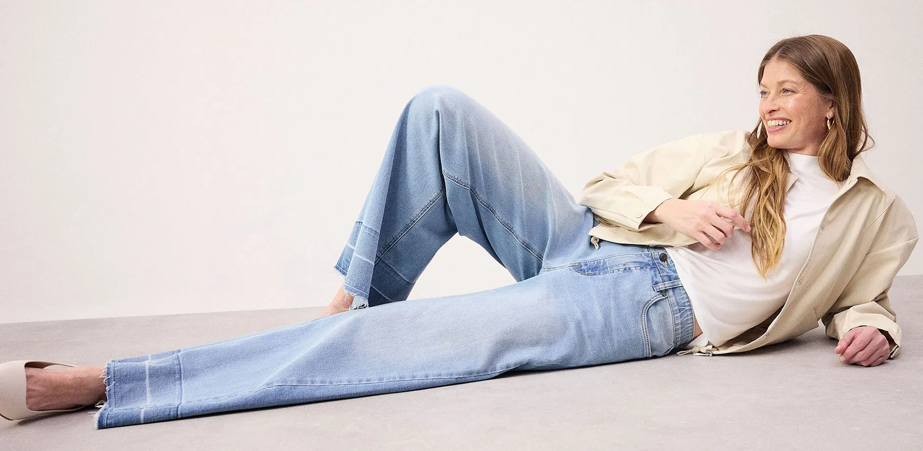 Avslappnad look med vida jeans, vit topp och beige jacka.

