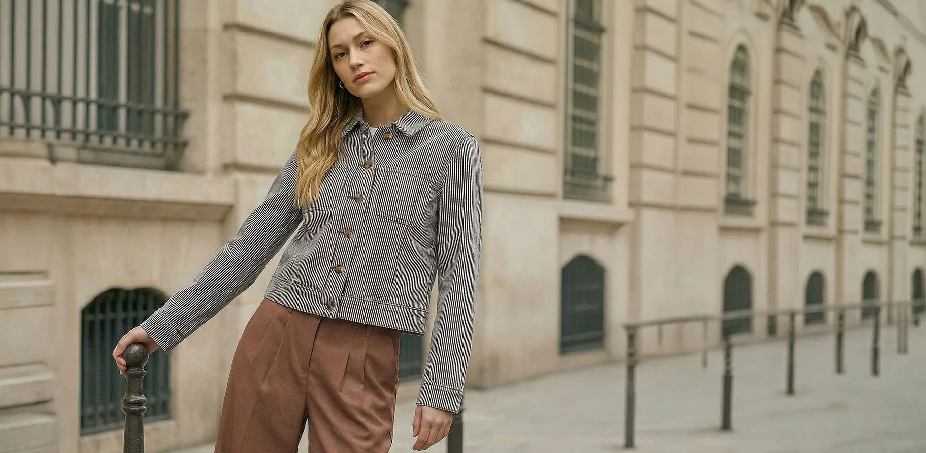 Svartrandig &ouml;verg&aring;ngsjacka kombinerad med bruna byxor.

