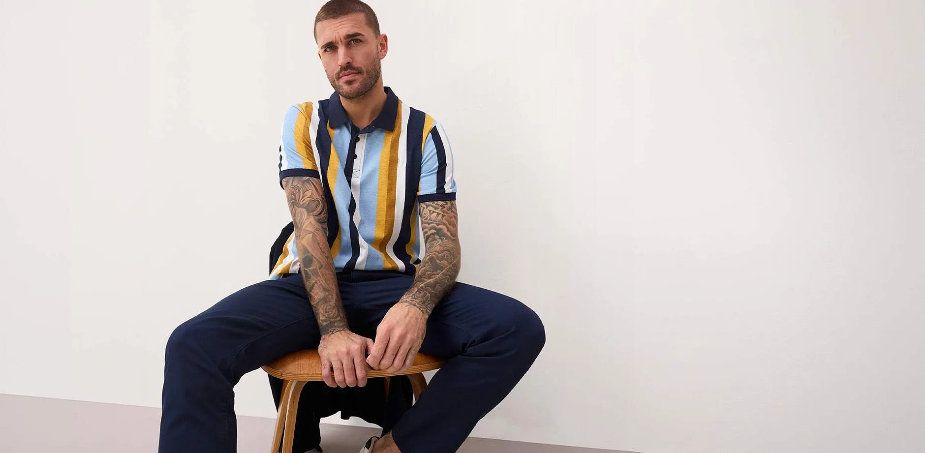 Randig pik&eacute;tr&ouml;ja i bl&aring;tt, gult och vitt. M&ouml;rkbl&aring; byxor.

