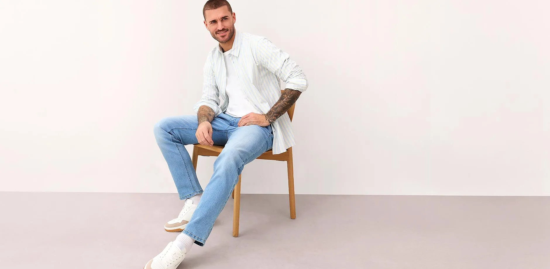 Vit, randig skjorta, ljusbl&aring; jeans och vita sneakers.