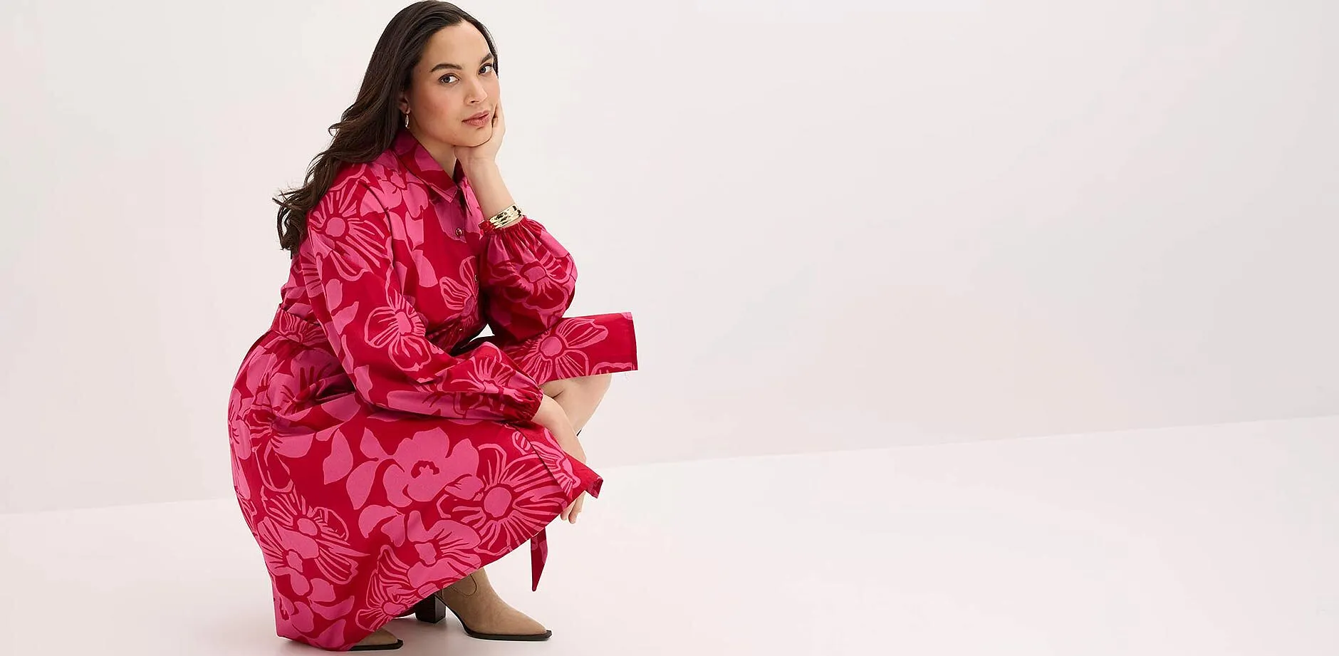 I&ouml;gonfallande r&ouml;d kl&auml;nning med blomm&ouml;nster, l&aring;nga &auml;rmar och krage.