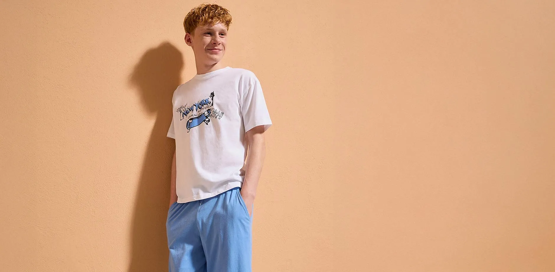 En pojke b&auml;r en vit T-shirt med tryck.
