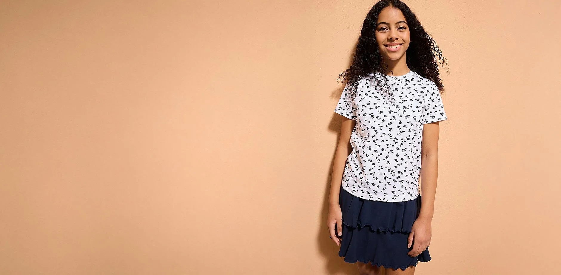 En flicka b&auml;r en vit T-shirt med m&ouml;nster.