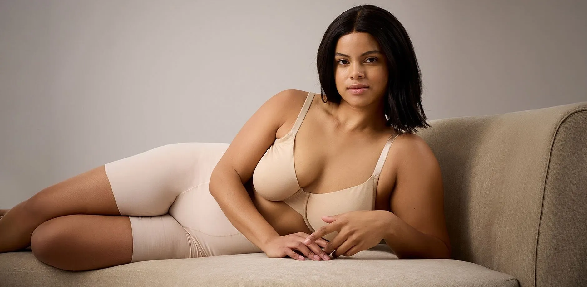 Beiga underkl&auml;der framh&auml;ver naturlig sk&ouml;nhet. Elegant silhuett vilar avslappnat p&aring; en kr&auml;mf&auml;rgad soffa.