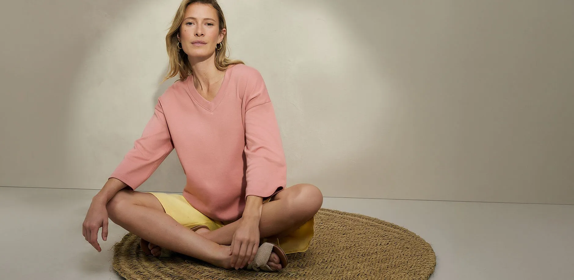 Kvinnan b&auml;r en rosa blus med gula shorts