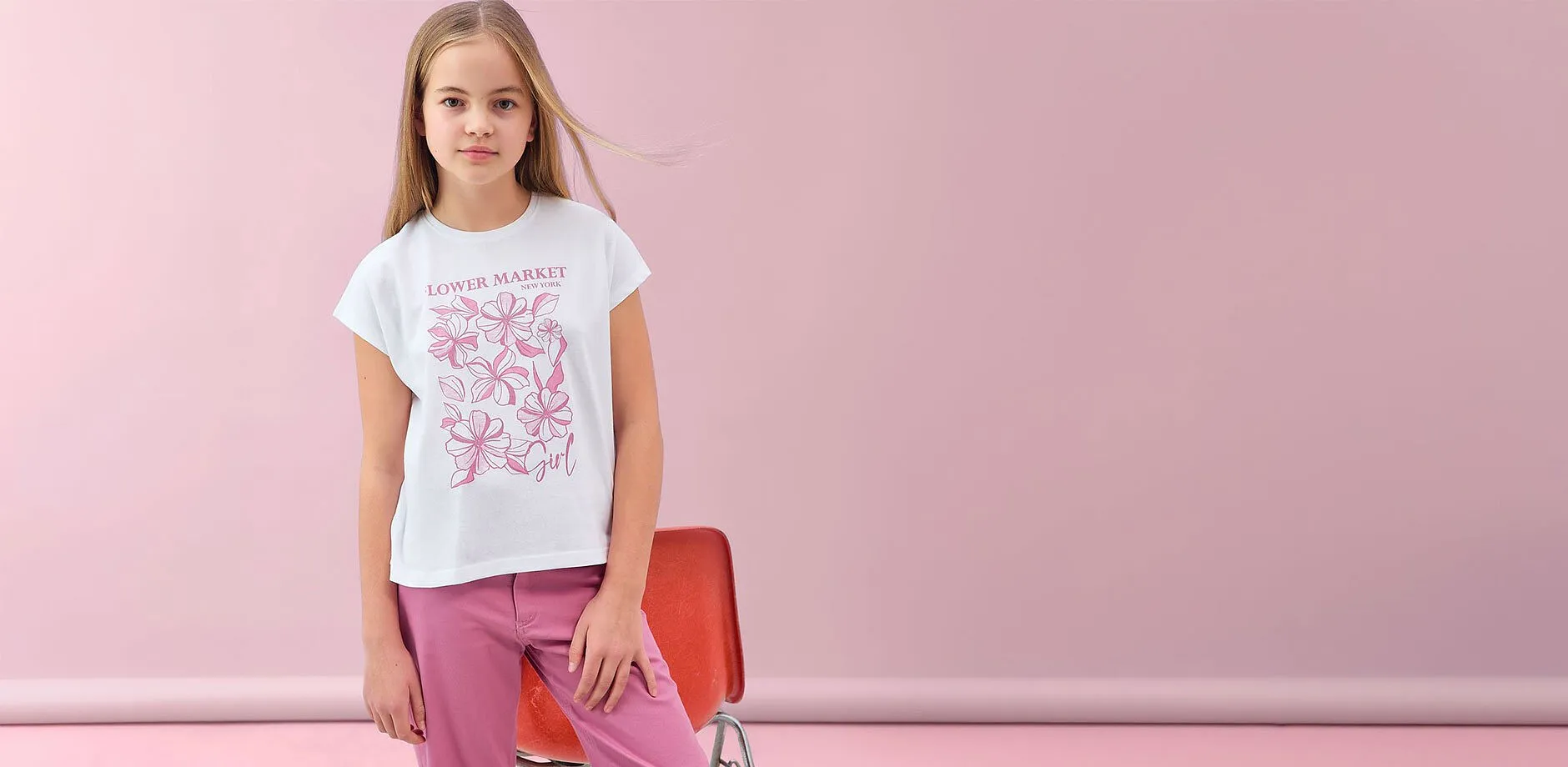 Vit t-shirt med rosa blomm&ouml;nster och rosa byxor.