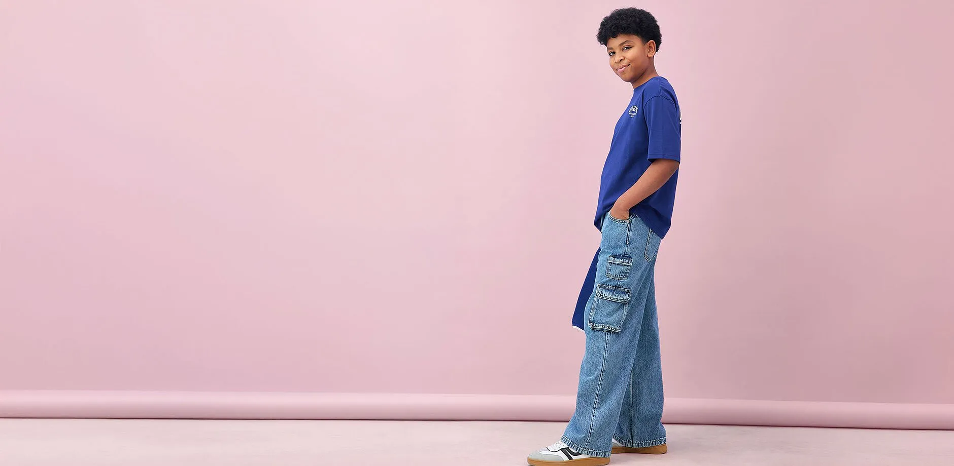 Pojken b&auml;r en bl&aring; t-shirt och vida cargojeans.