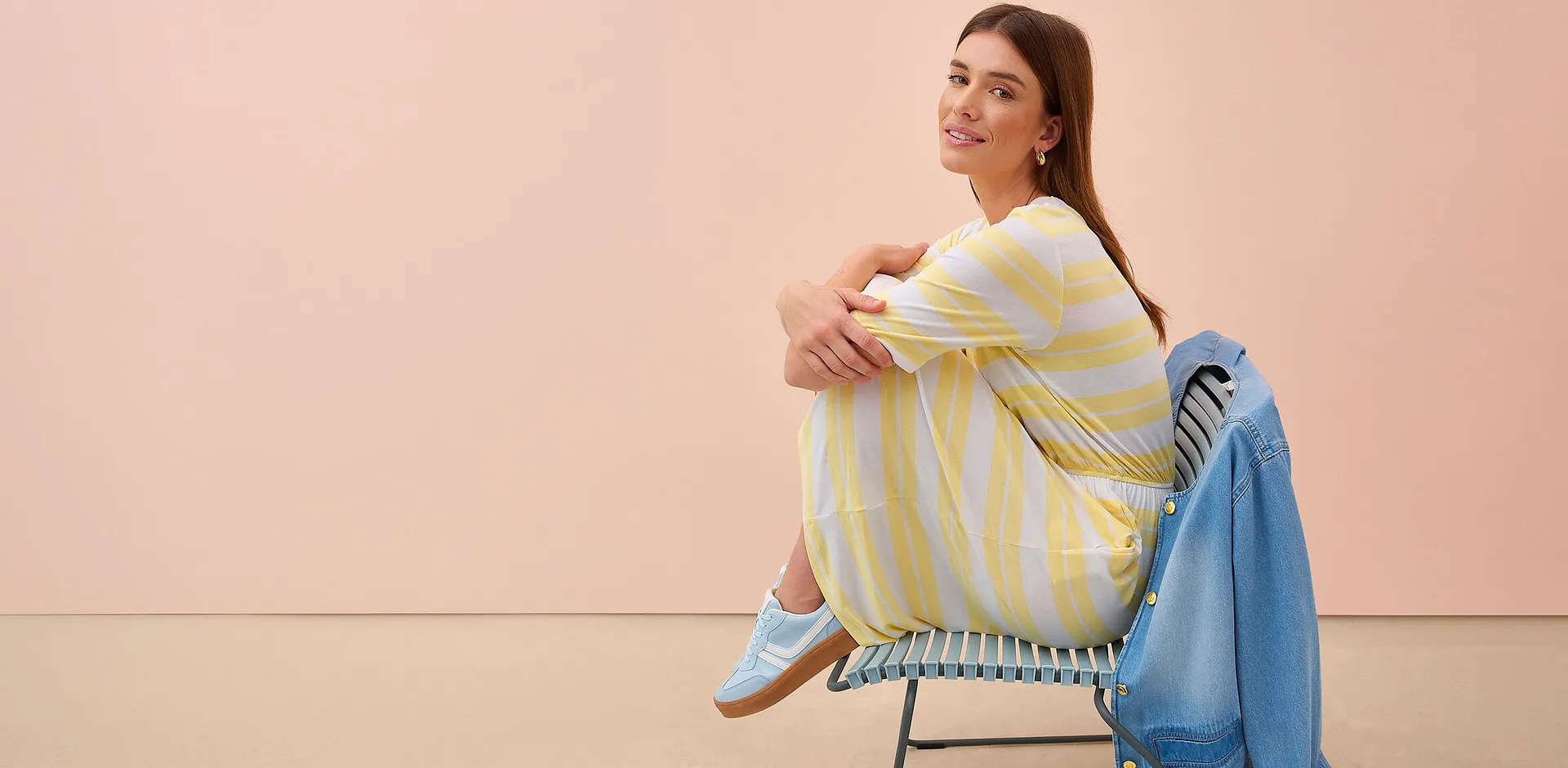 Kvinna b&auml;r gul-vitrandig kl&auml;nning.

