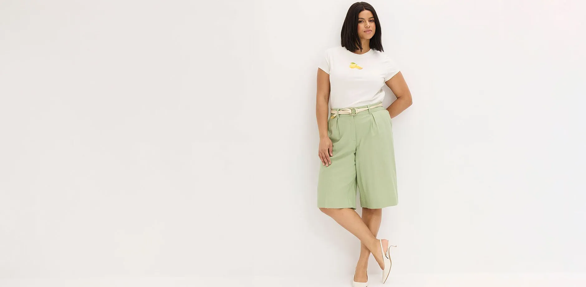 Vit T-shirt, gr&ouml;na Bermuda-shorts och beiga sandaler.

