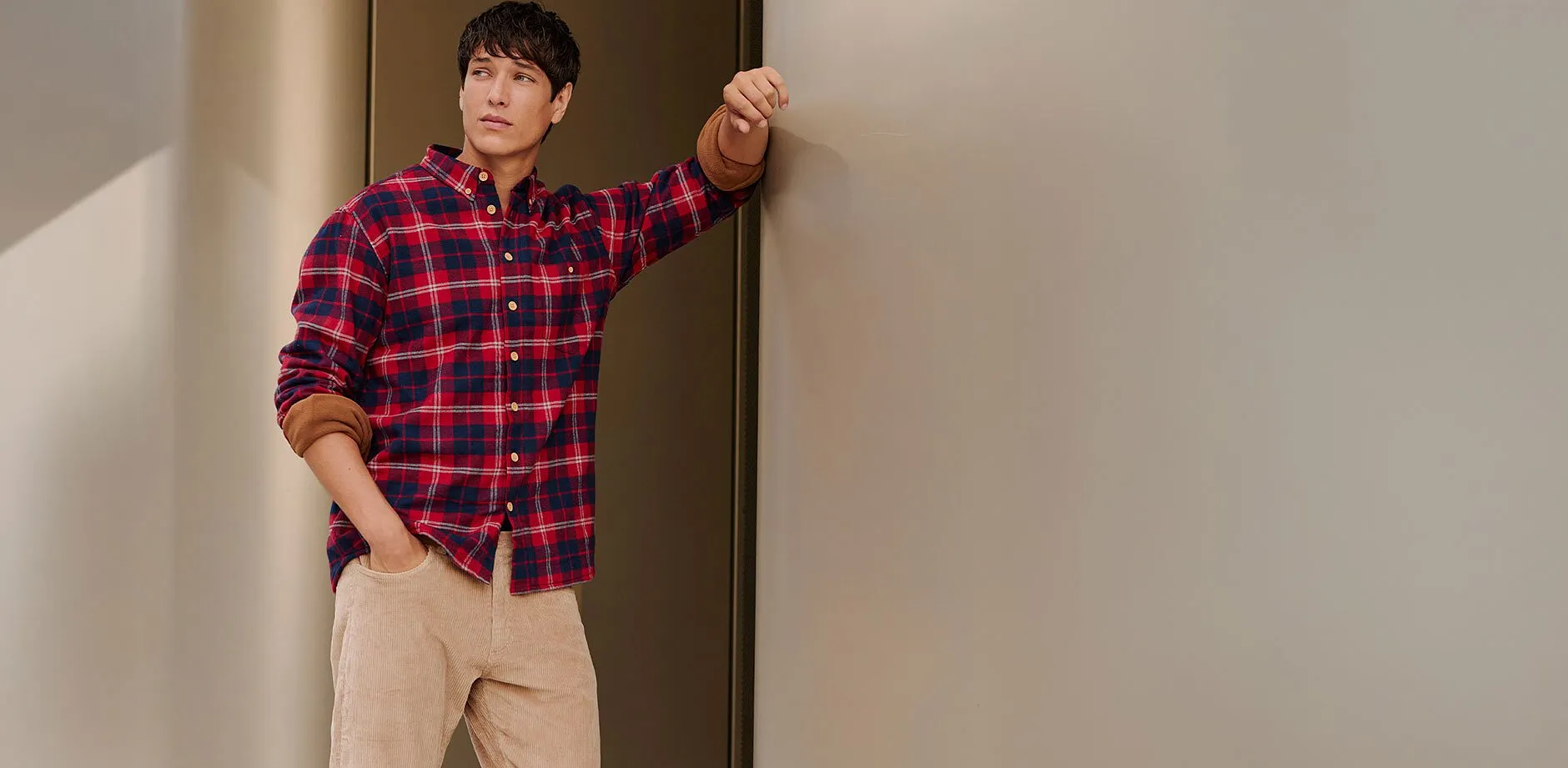Avslappnad look med rutig skjorta i r&ouml;tt och bl&aring;tt, och beige byxor.