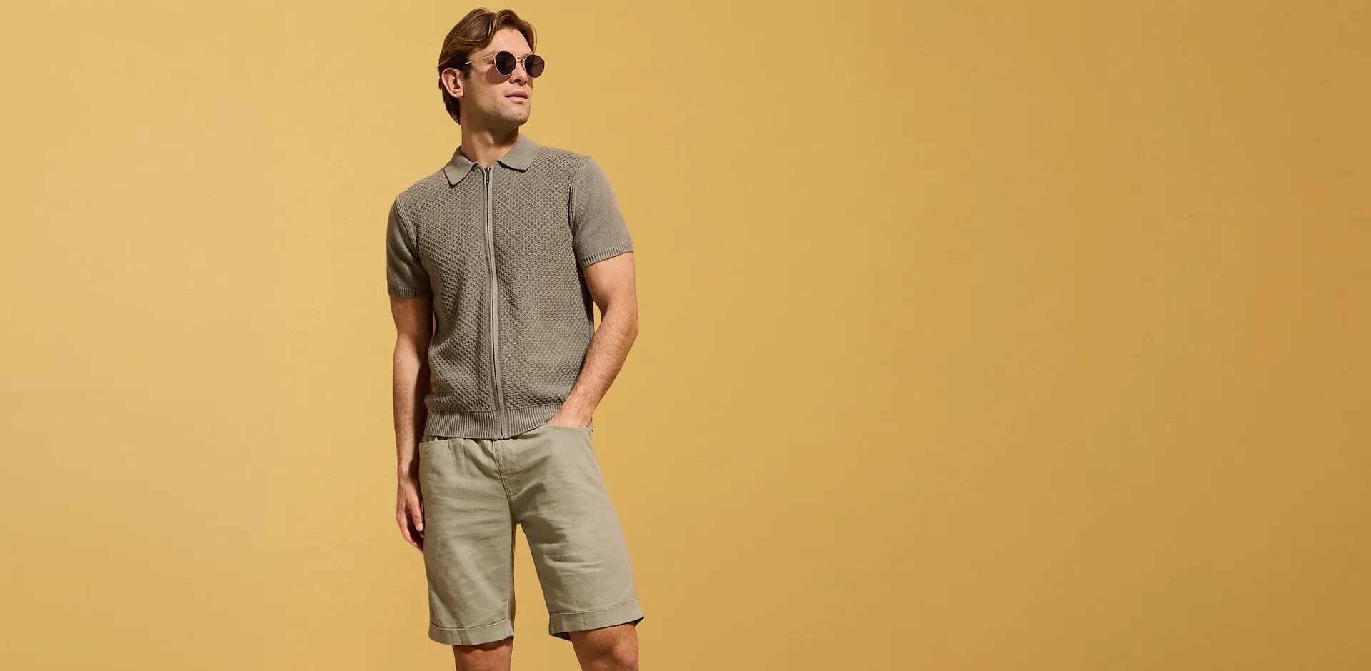 Gr&aring; stickad pik&eacute;tr&ouml;ja med dragkedja och beige shorts f&ouml;r en avslappnad sommarlook.