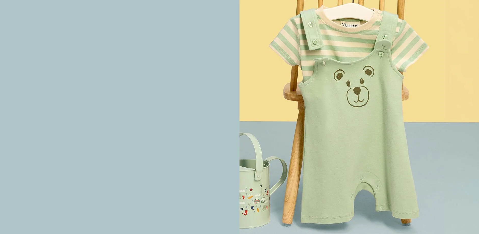S&ouml;t mintgr&ouml;n babyh&auml;ngselbyxa med bj&ouml;rnmotiv och randig T-shirt upph&auml;ngd p&aring; en tr&auml;stol.