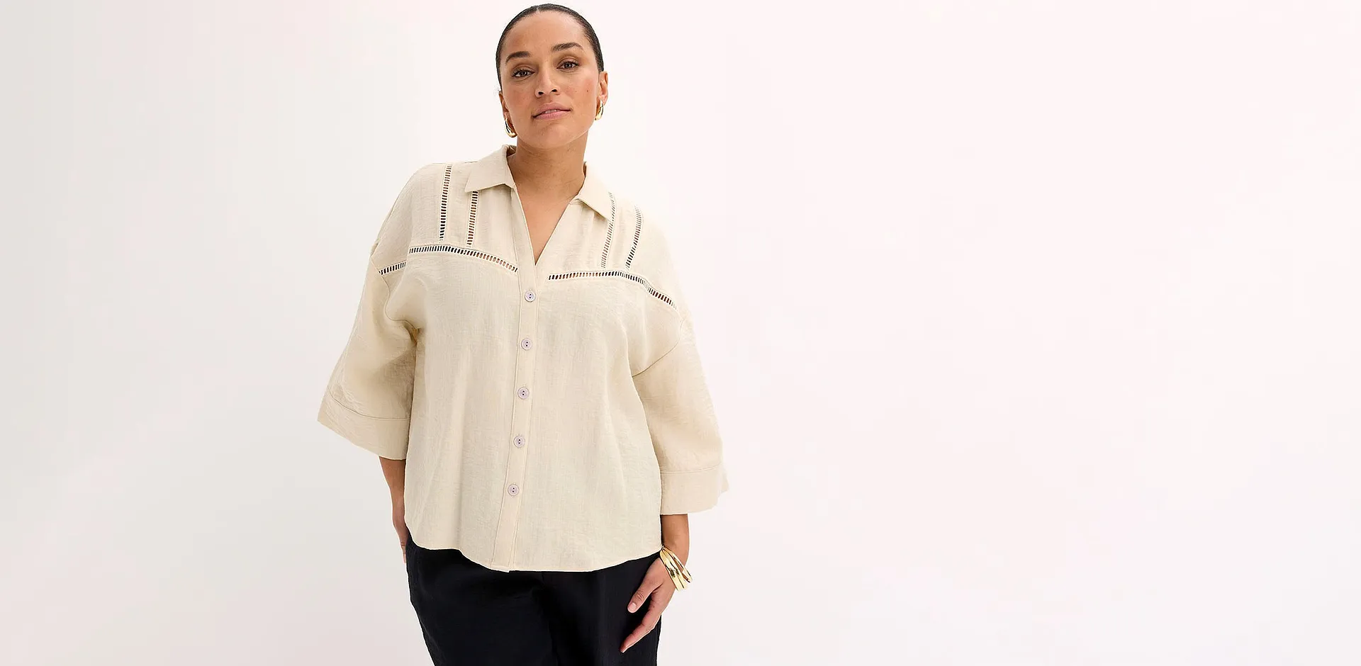 Beige blus med klassisk krage, kombinerad med svarta byxor.

