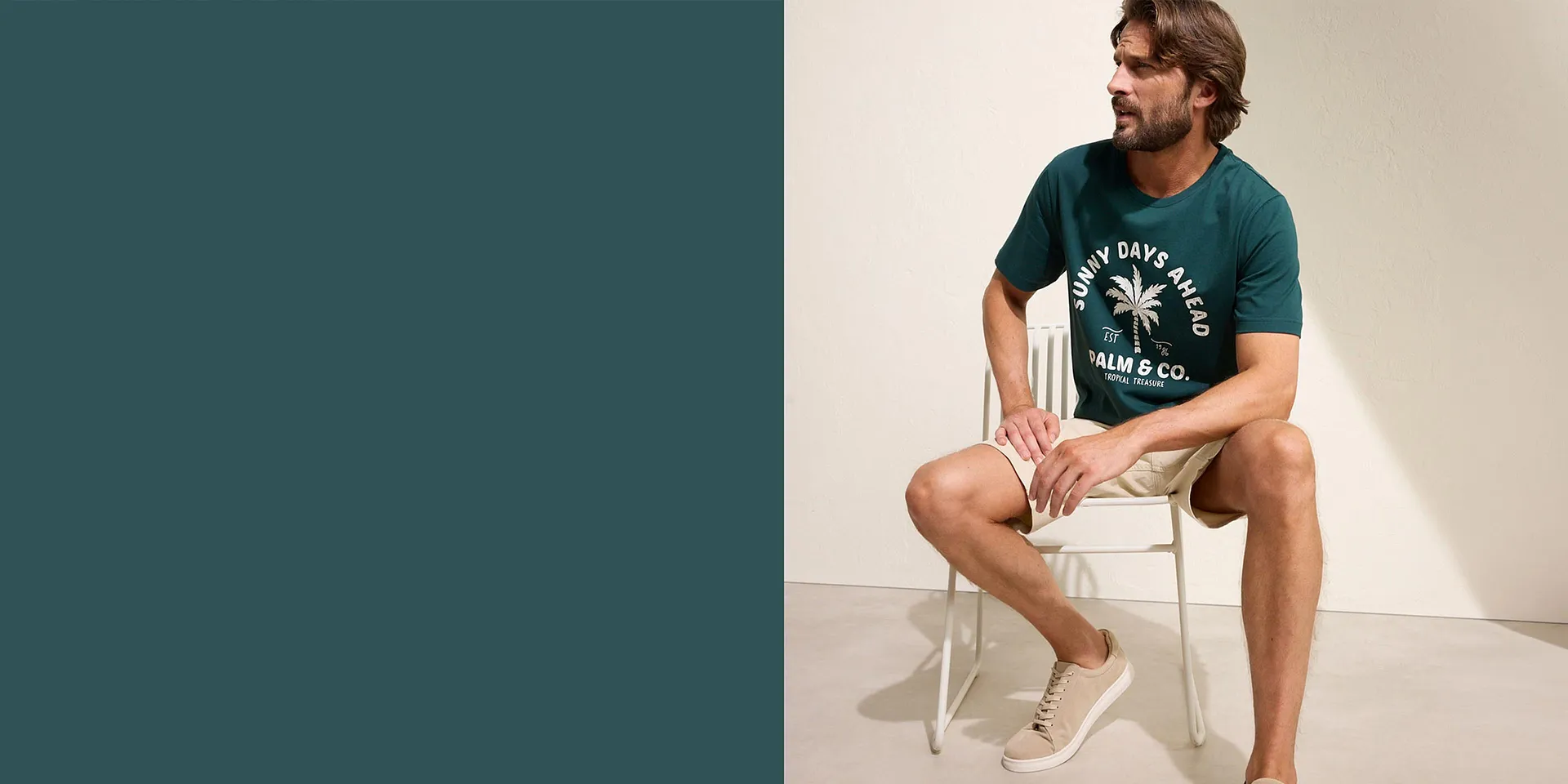 Mannen har p&aring; sig en gr&ouml;n T-shirt med palmtryck, beiga shorts och vita sneakers.

