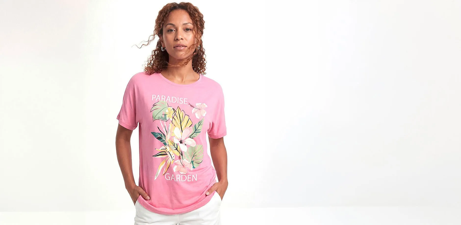 Rosa T-shirt med blommotiv och vita byxor.

