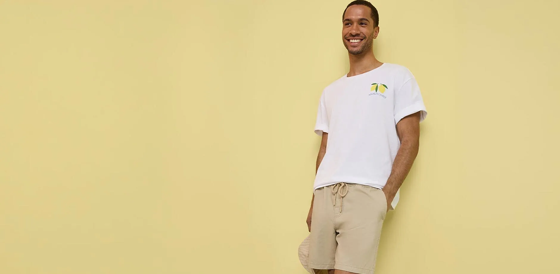 Avslappnad outfit med en vit T-shirt, beige shorts och vita sneakers.

