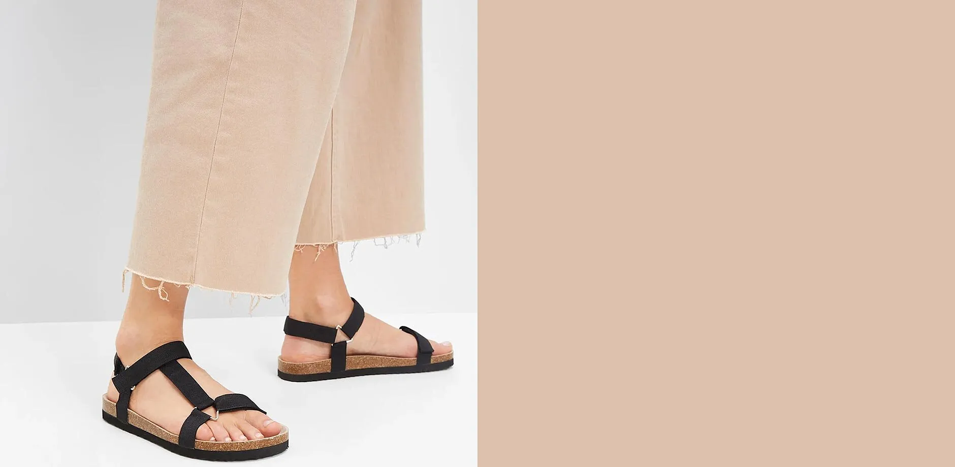 Svarta sandaler med remmar kompletterar de beige vida byxorna perfekt f&ouml;r en avslappnad look.