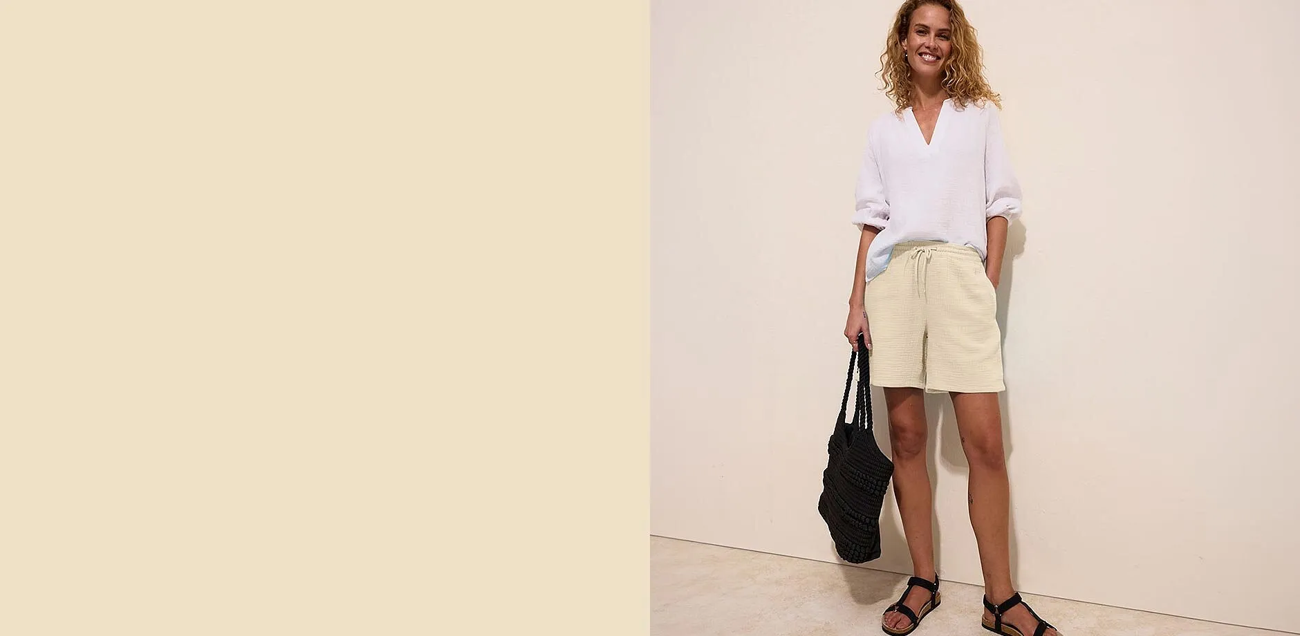 Vit blus, beigef&auml;rgade muslinshorts och svarta sandaler f&ouml;r en avslappnad sommarlook.