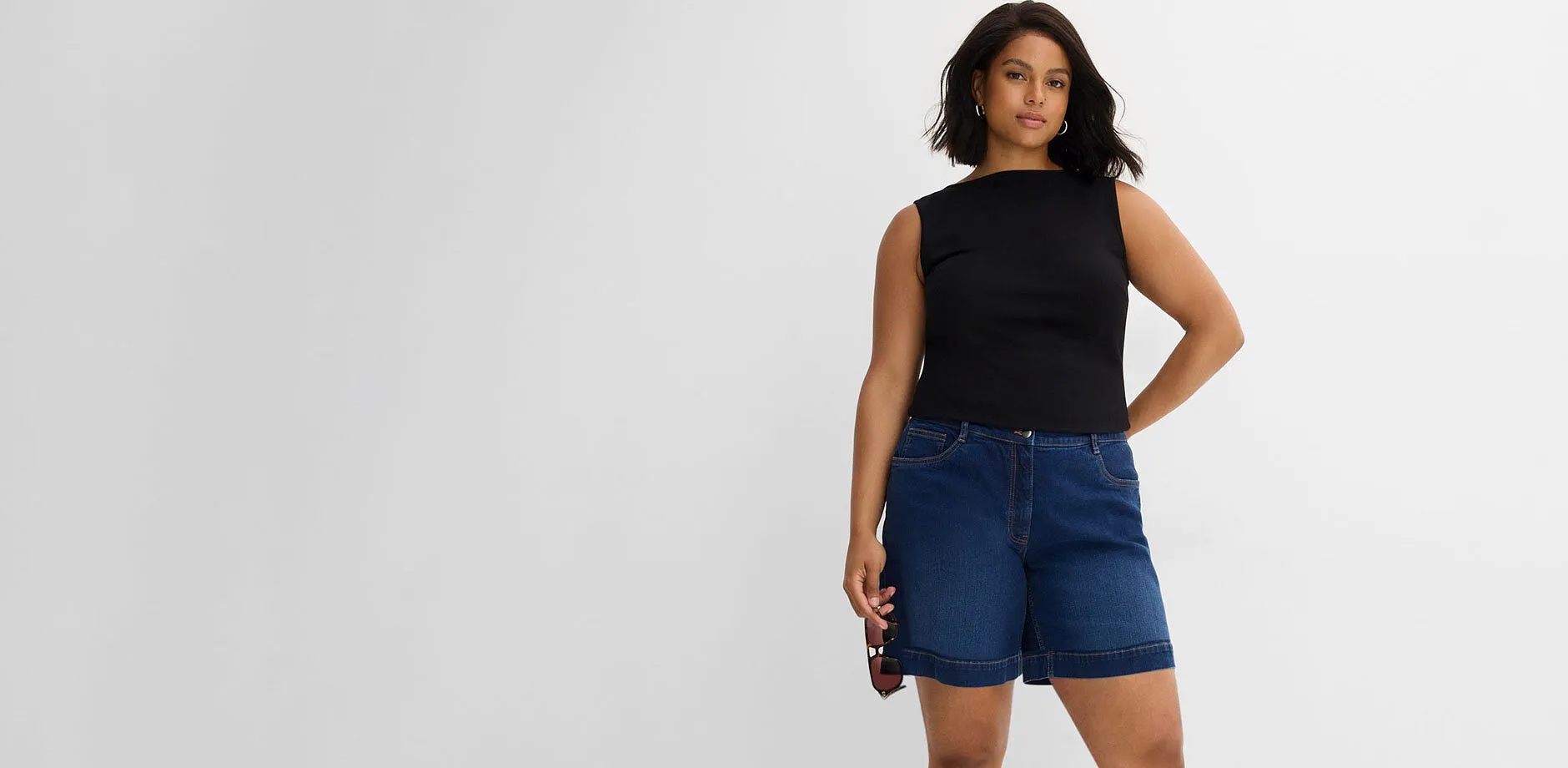 Svart linne och avslappnade, bl&aring; jeansshorts.
