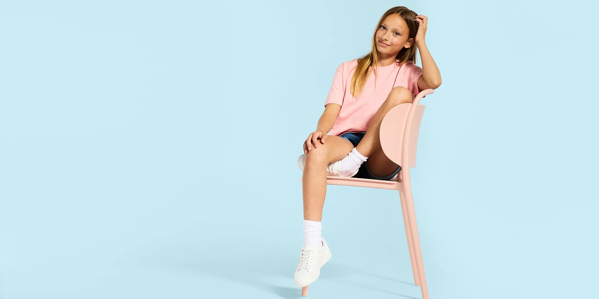 Rosa T-shirt, jeansshorts, vita strumpor och sneakers.

