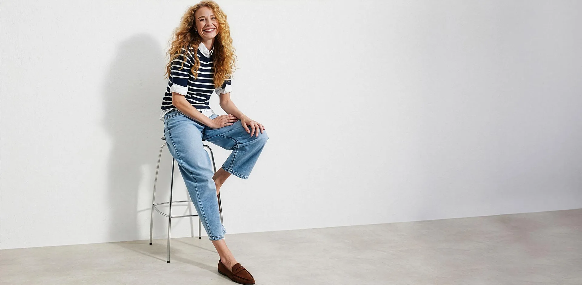 Randig tr&ouml;ja &ouml;ver en blus, ljusa jeans och bruna loafers.