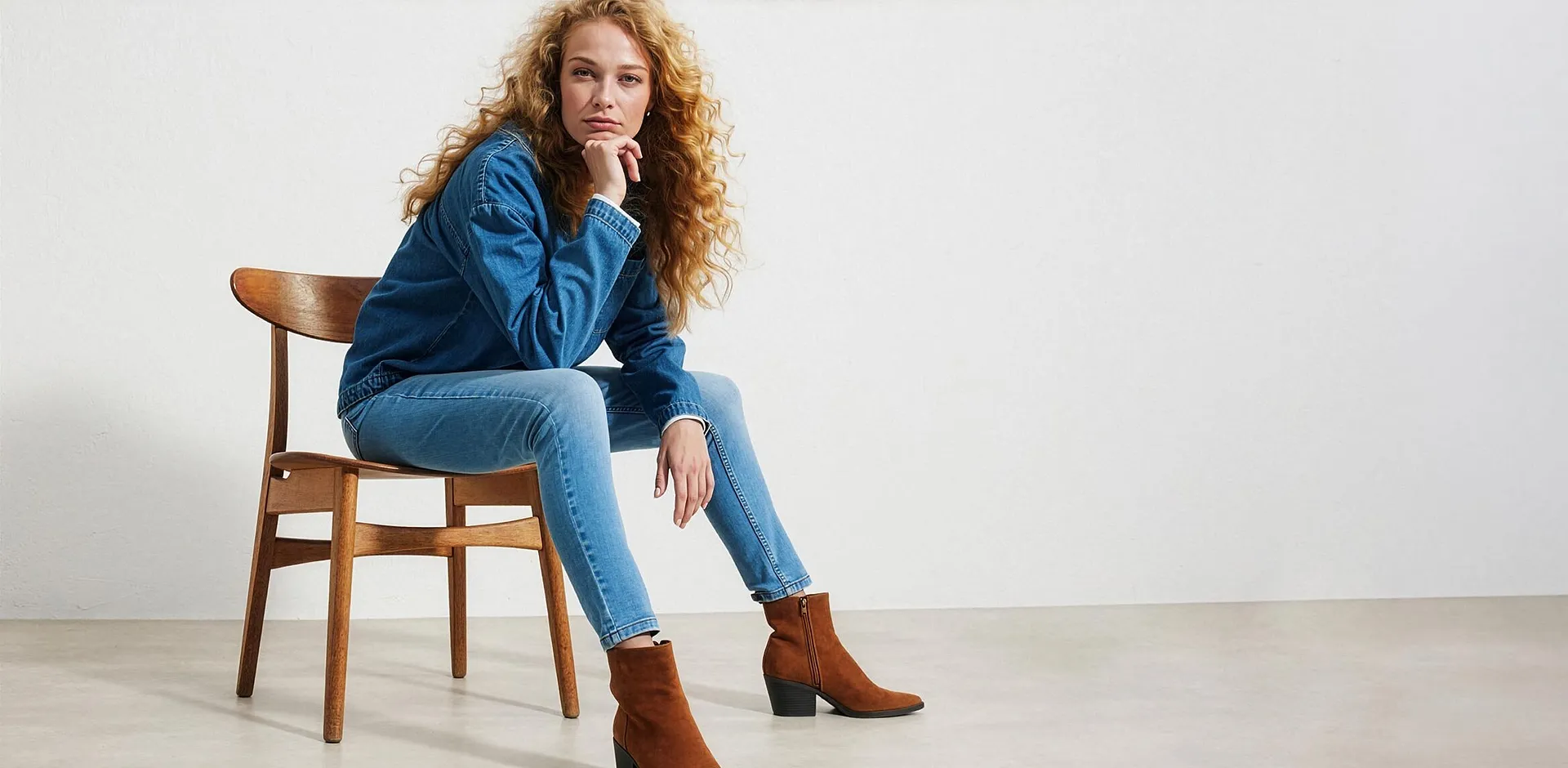 Hon har p&aring; sig en bl&aring; jeansjacka, jeans och stils&auml;kra bruna st&ouml;vletter.