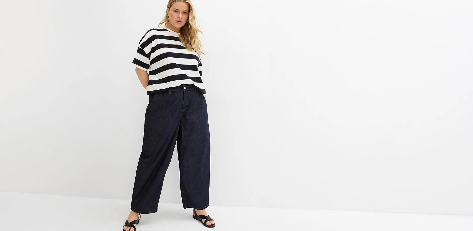 Randig &ouml;verdel, vida, m&ouml;rkbl&aring; jeans och svarta sandaler.