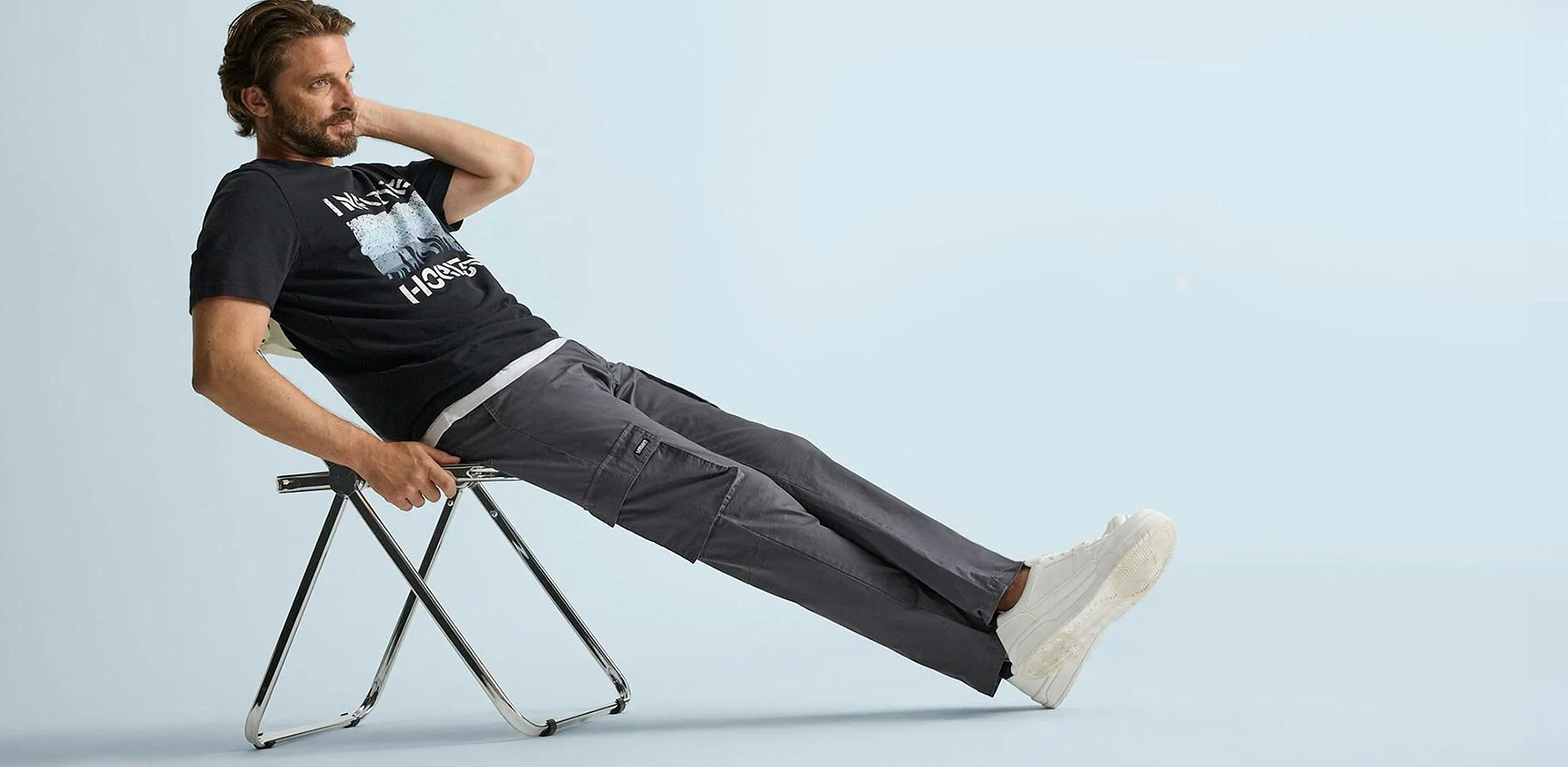 Svart T-shirt med tryck, bekv&auml;ma, gr&aring; cargobyxor och lediga vita sneakers.