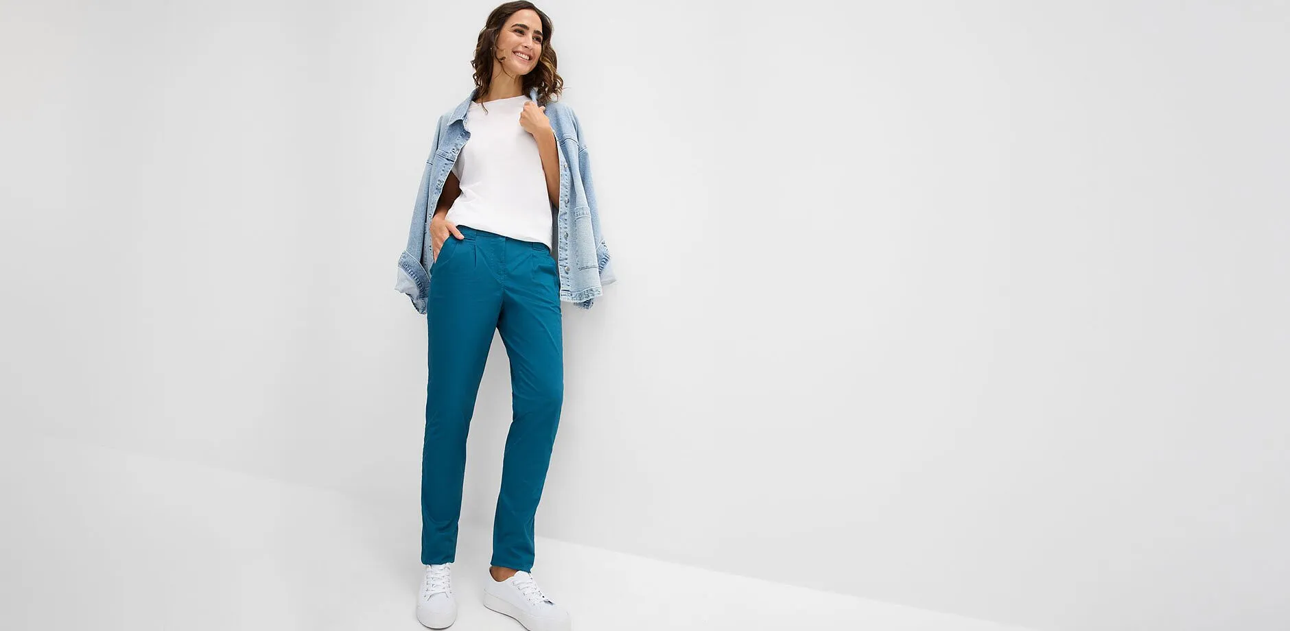 Turkosa byxor, vit topp, ledig jeansjacka och vita sneakers.
