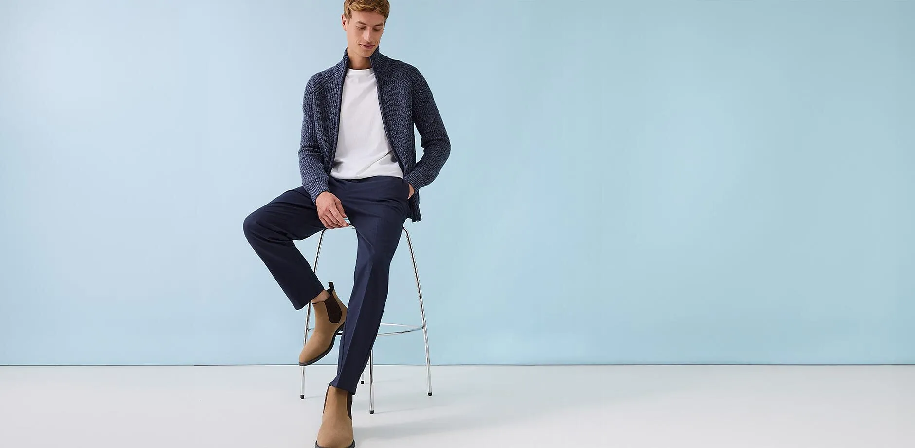 M&ouml;rkbl&aring; cardigan &ouml;ver en vit T-shirt, tillsammans med eleganta byxor och beige mockaboots.