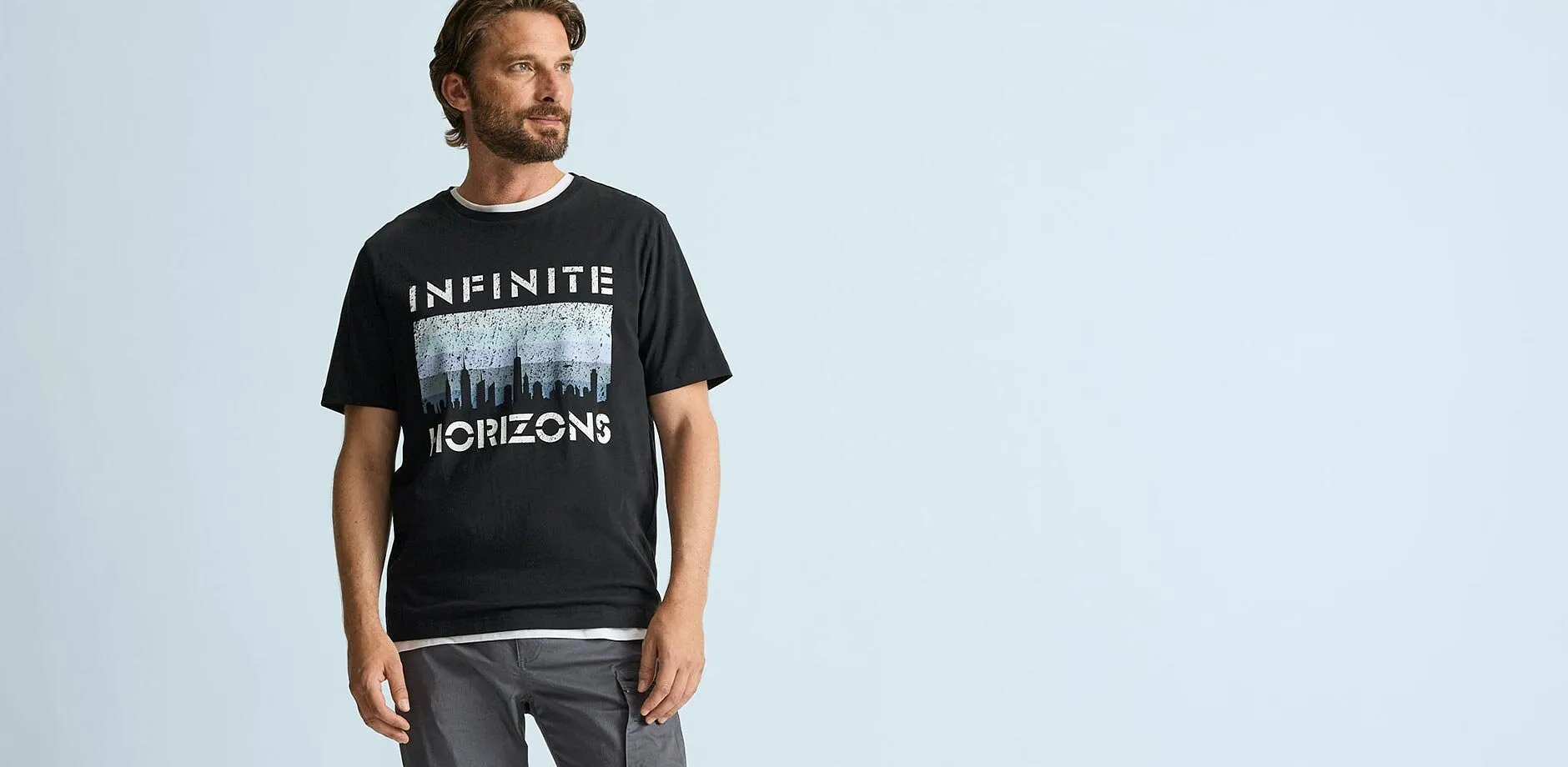 Svart T-shirt med texttrycket "Infinite Horizons" och lediga, gr&aring; cargobyxor.