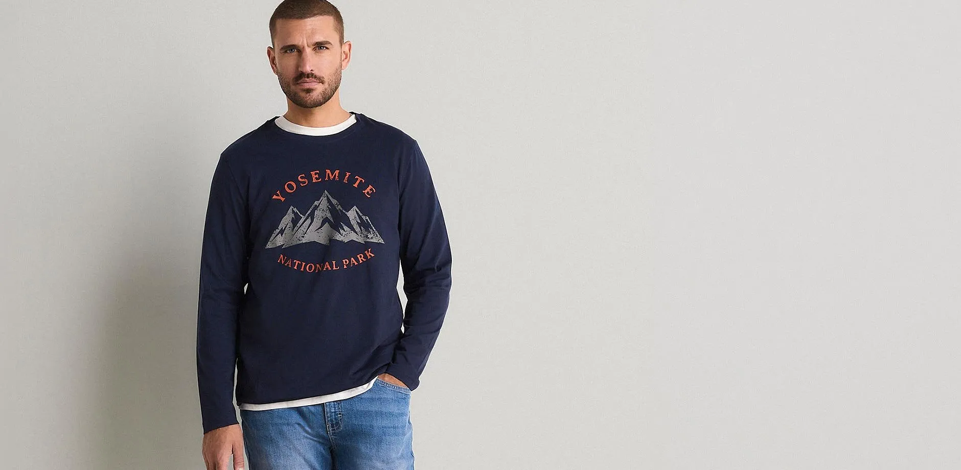 En man med jeans och m&ouml;rkbl&aring;, l&aring;ng&auml;rmad tr&ouml;ja med Yosemite National Park-tryck
