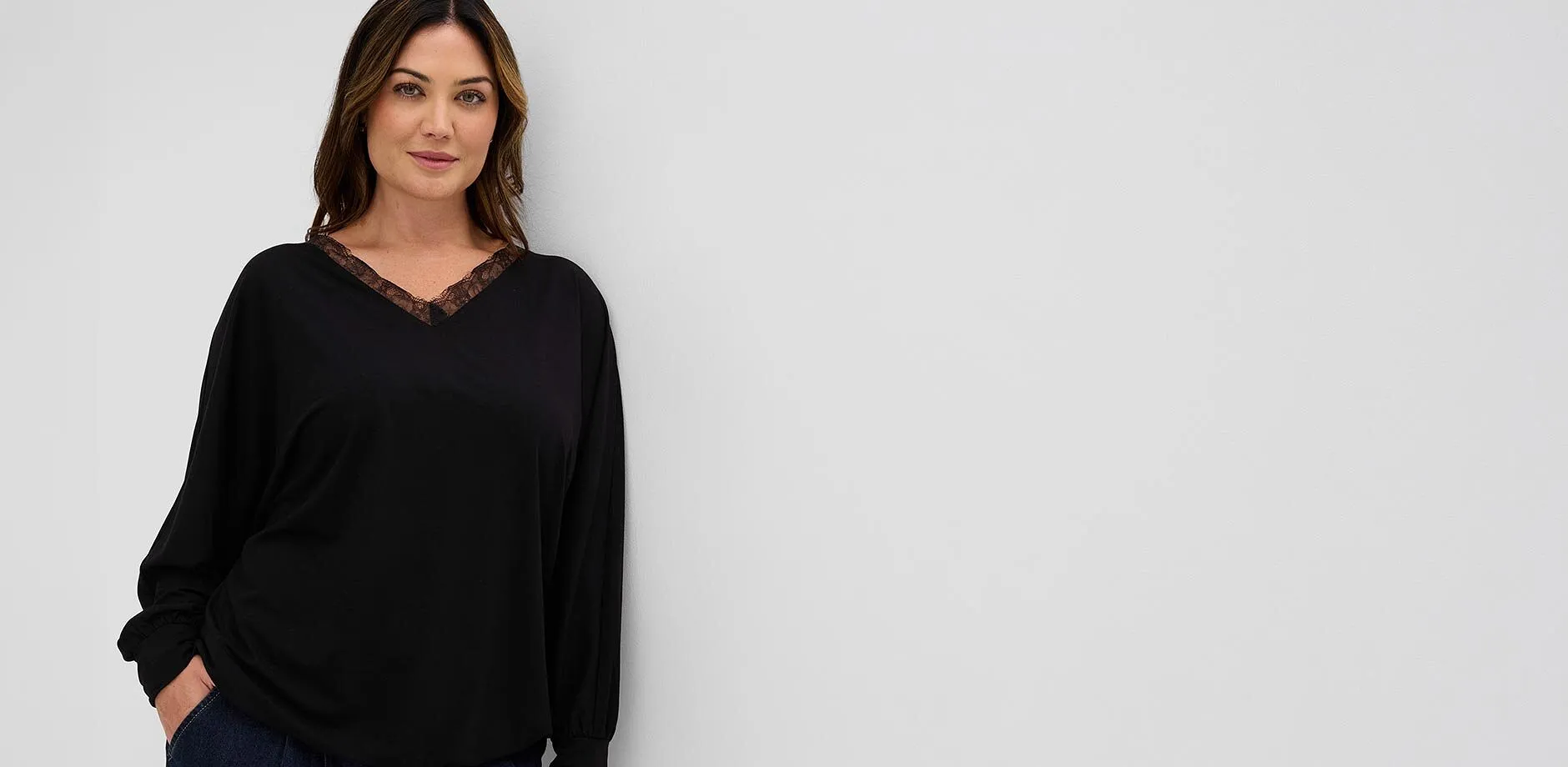 Modern, svart l&aring;ng&auml;rmad topp med skir spets vid V-ringningen och m&ouml;rka jeans till det.
