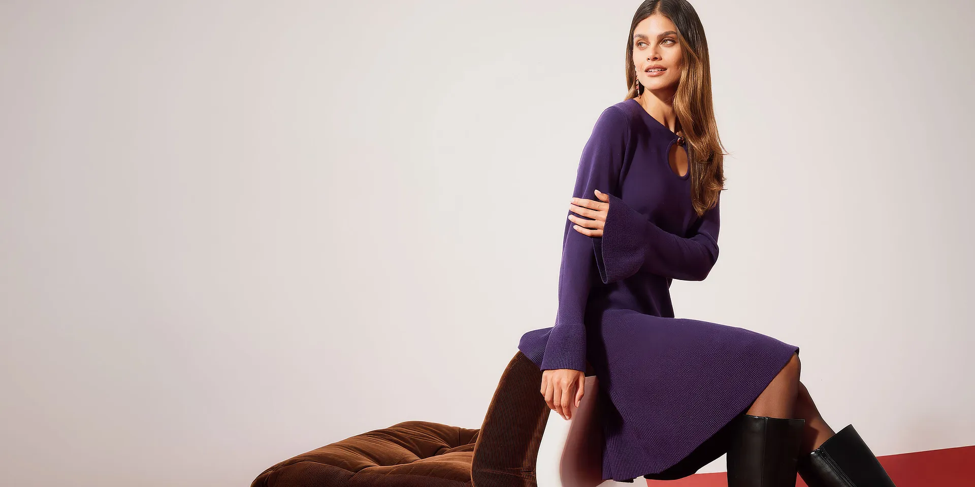 Elegant, violett stickad kl&auml;nning med vida &auml;rmar, kombinerad med h&ouml;ga svarta st&ouml;vlar.