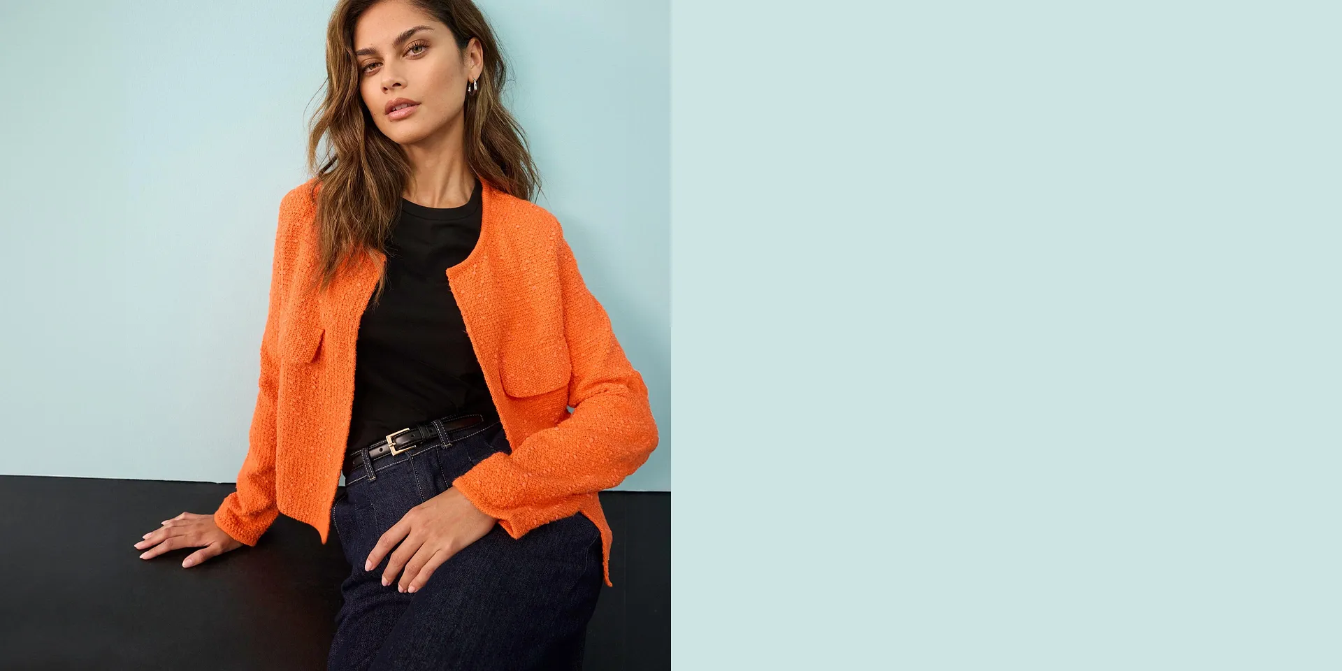 Ljust orangef&auml;rgad cardigan &ouml;ver en svart topp, kombinerat med jeans och ett elegant b&auml;lte.

