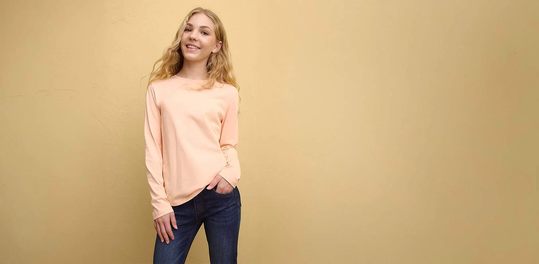 Rosa l&aring;ng&auml;rmad tr&ouml;ja med bl&aring; jeans.