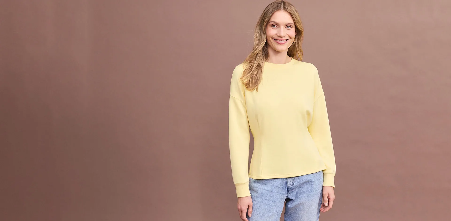 Brun l&aring;ng&auml;rmad tr&ouml;ja med bekv&auml;ma bl&aring; jeans.