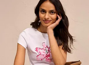 Den vita T-shirten med ett rosa blommotiv utstrålar lätthet.