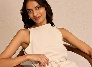 Elegantes, cremefarbenes Kleid mit hohem Ausschnitt und Gürtel betont die schlanke Silhouette.